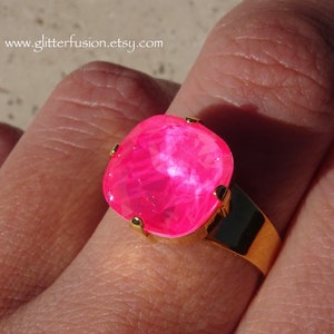May include: A bright pink ring with a large square-shaped gemstone set in a gold band.