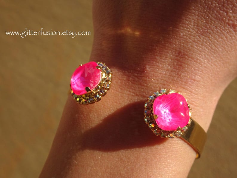 May include: Gold cuff bracelet with two large pink gem stones surrounded by clear rhinestones.