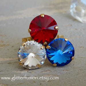 May include: Three rings with large, faceted gemstone settings in red, white, and blue. The gemstones are round and set in gold-colored metal. The website address www.glitterfusion.etsy.com is visible at the bottom.