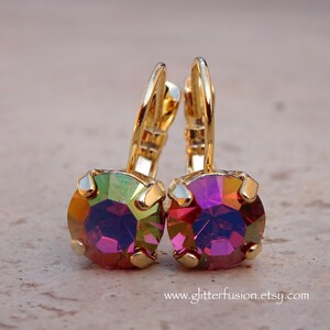 May include: Gold hoop earrings with iridescent purple and green round crystal stones.