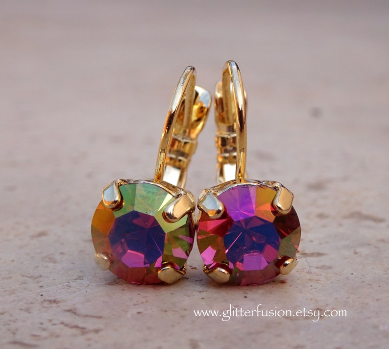 May include: Gold hoop earrings with iridescent purple and green round crystal stones.