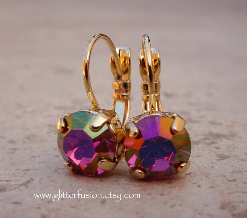 May include: A pair of gold hoop earrings with iridescent purple gemstones. The earrings have a simple design and are perfect for everyday wear.