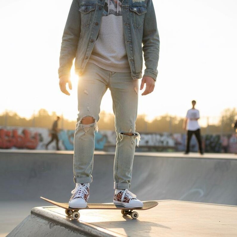 Puede incluir: Una persona de pie sobre una patineta en un parque de patinaje. La persona lleva vaqueros claros rasgados, zapatillas blancas con un dise&ntilde;o estampado y una chaqueta vaquera. La patineta es marr&oacute;n.