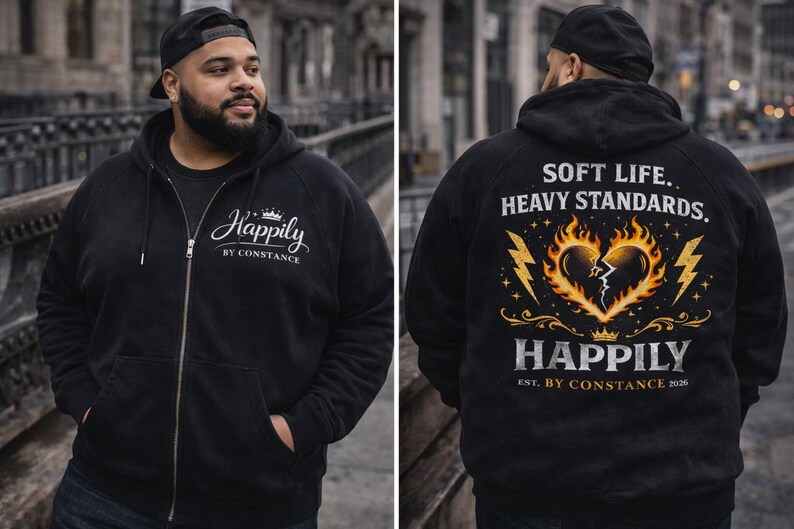 Puede incluir: Sudadera con capucha negra con cremallera con el texto "Happily by Constance" en la parte delantera. La parte trasera presenta un gr&aacute;fico de un coraz&oacute;n en llamas con el texto "Soft Life, Heavy Standards" y "Happily Est. By Constance 2026".
