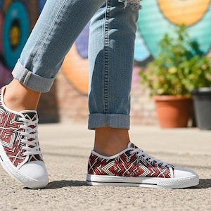 Puede incluir: Zapatillas de lona con suela blanca y un estampado geom&eacute;trico rojo, negro y blanco. Los zapatos de corte bajo tienen cordones blancos y se usan con vaqueros. Las zapatillas son de estilo casual.