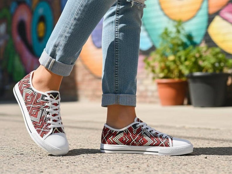 Puede incluir: Zapatillas de lona con suela blanca y un estampado geom&eacute;trico rojo, negro y blanco. Los zapatos de corte bajo tienen cordones blancos y se usan con vaqueros. Las zapatillas son de estilo casual.