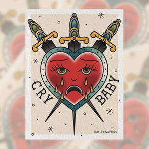 May include: A traditional tattoo-style illustration of a red heart with a sad face and tears, pierced by three swords. The words "CRY BABY" are written around the heart.