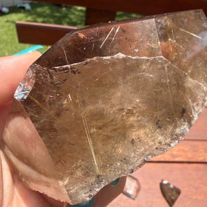 Gema de cuarzo rutilado dorado de forma irregular: cristal pulido con zonas sin tratar.