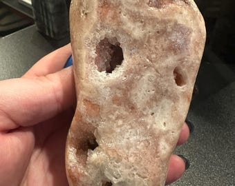 May include: A large, irregularly shaped, pink and white geode with several large openings revealing the crystal structure inside.