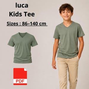 Peut inclure: Un t-shirt vert sauge à col en V et manches courtes. Le texte indique : luca Kids Tee Sizes : 86-140 cm. Une icône rouge avec le texte PDF est visible. Le t-shirt est présenté seul et porté par une personne avec un pantalon beige.