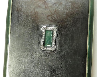 May include: A black rectangular box with a green border and a small green stone set in a silver frame. The box has a silver clasp and a small green stone set in the center of the lid.