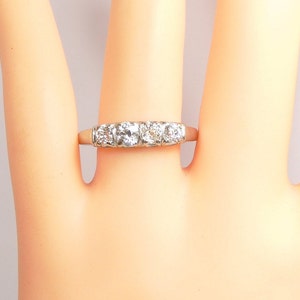 Puede incluir: Un anillo de banda de plata con cinco diamantes redondos transparentes engastados en fila.