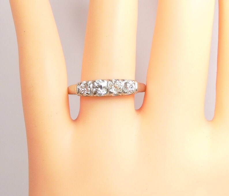 Puede incluir: Un anillo de banda de plata con cinco diamantes redondos transparentes engastados en fila.