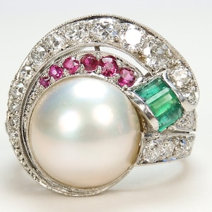 Puede incluir: Un anillo de perla blanca con un halo de diamantes y rubíes, y acentos de esmeralda.