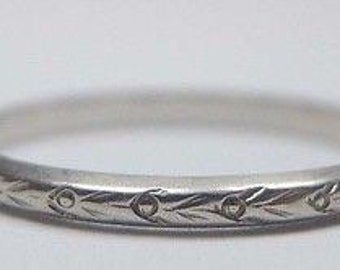 May include: A silver wedding band with a delicate floral design engraved around the band.