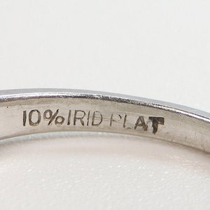 Puede incluir: Primer plano del interior de un anillo de plata con la inscripci&oacute;n "10% IRID PLAT" grabada en la banda.