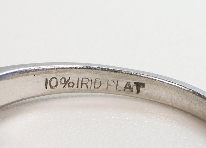 Puede incluir: Primer plano del interior de un anillo de plata con la inscripci&oacute;n "10% IRID PLAT" grabada en la banda.