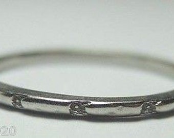 May include: A silver band ring with a simple, textured design. The ring is smooth and has a subtle shine.