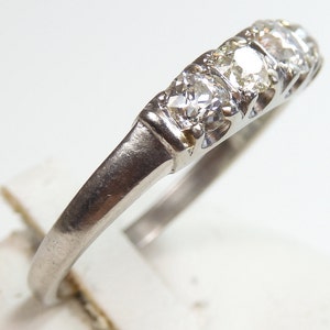 Puede incluir: Un anillo de banda de plata con cinco peque&ntilde;os diamantes redondos engastados en fila.