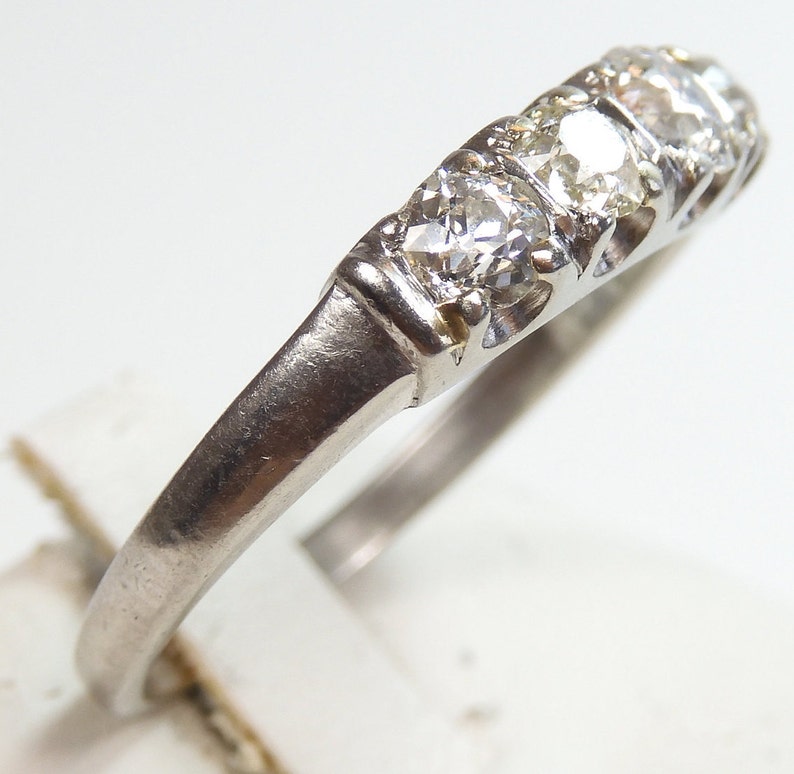 Puede incluir: Un anillo de banda de plata con cinco peque&ntilde;os diamantes redondos engastados en fila.