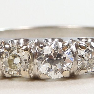 Puede incluir: Un anillo de banda de plata con cinco diamantes redondos engastados en fila. Los diamantes son claros y brillantes.