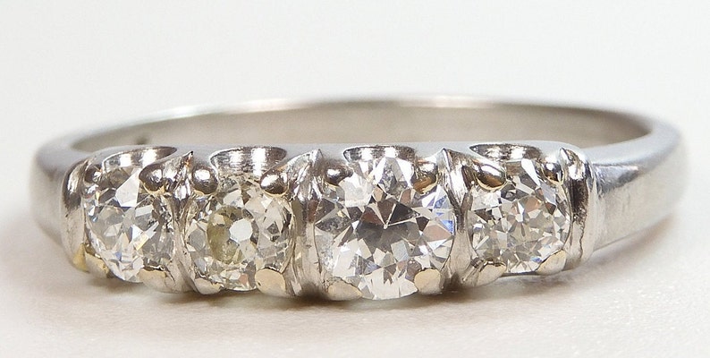 Puede incluir: Un anillo de banda de plata con cinco diamantes redondos engastados en fila. Los diamantes son claros y brillantes.