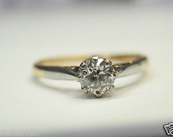 May include: A gold and silver engagement ring with a round, clear diamond.
