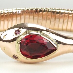 May include: A gold snake bracelet with a red gemstone set in the snake's head.