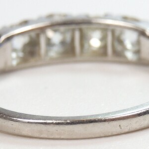 Puede incluir: Un anillo de banda de plata con cinco diamantes de forma cuadrada engastados en fila.