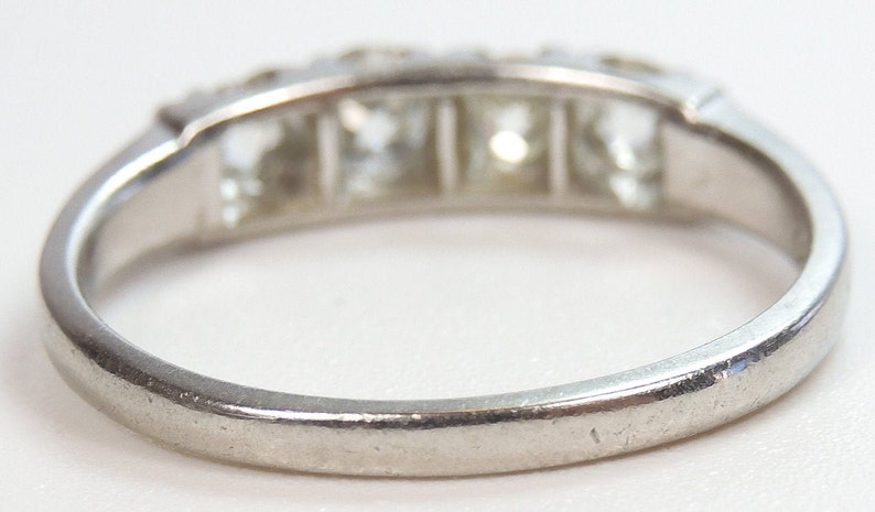 Puede incluir: Un anillo de banda de plata con cinco diamantes de forma cuadrada engastados en fila.