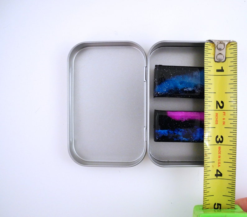 Handpainted nebula magnet set, one primarily blue and the other pink and blue covered and resin, painted in gold on the back and covered and initialled with date.