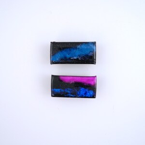 Handpainted nebula magnet set, one primarily blue and the other pink and blue covered and resin, painted in gold on the back and covered and initialled with date.