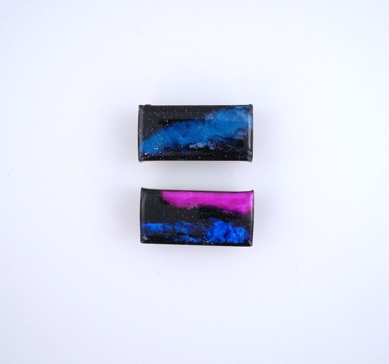 Handpainted nebula magnet set, one primarily blue and the other pink and blue covered and resin, painted in gold on the back and covered and initialled with date.