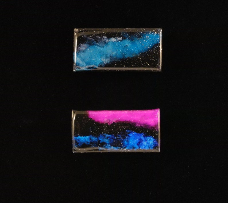 Handpainted nebula magnet set, nebula magnet set, one primarily blue and the other pink and blue covered and resin, painted in gold on the back and initialled with date.