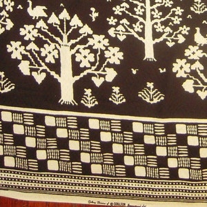 May include: Black and white fabric with a repeating pattern of stylized trees, birds, and geometric shapes. The fabric has a checkered border.