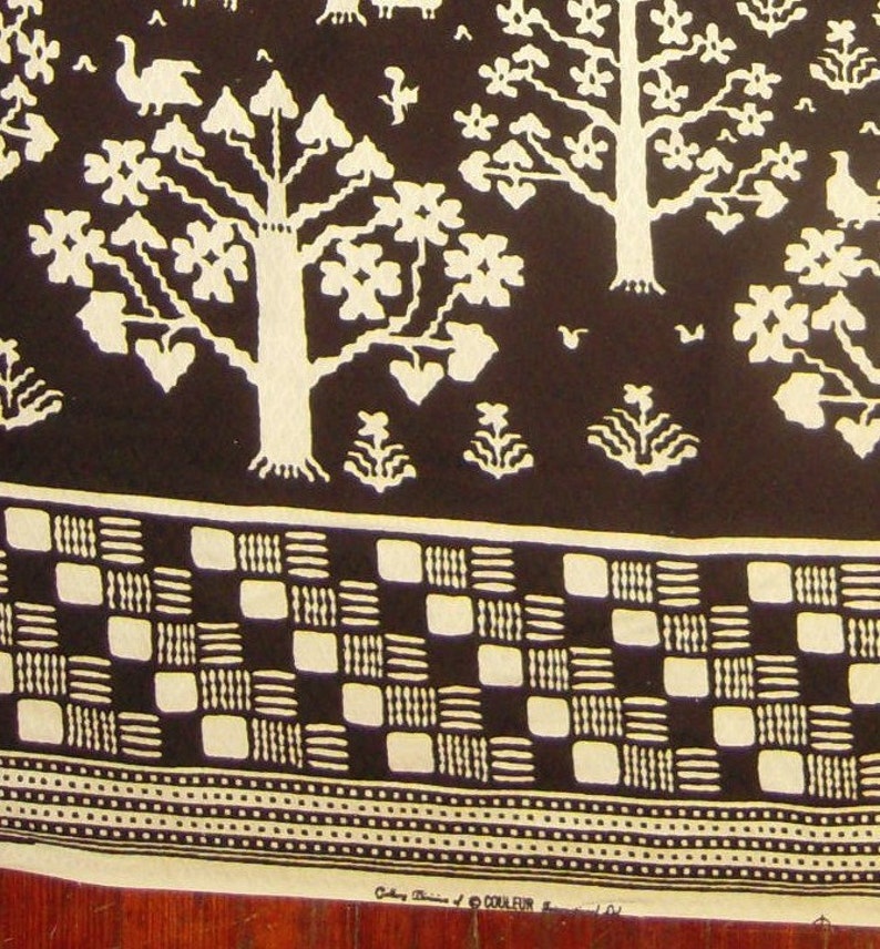 May include: Black and white fabric with a repeating pattern of stylized trees, birds, and geometric shapes. The fabric has a checkered border.