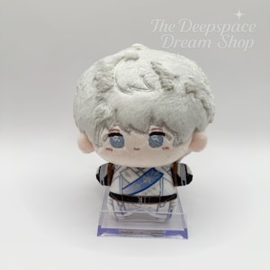 Puede incluir: Un muñeco de peluche con cabello gris claro, ojos azules y un atuendo blanco y azul. El muñeco está sobre un soporte de plástico transparente. El texto "The Deepspace Dream Shop" está en la esquina superior derecha.