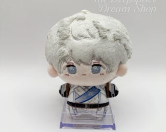 Puede incluir: Un muñeco de peluche con cabello gris claro, ojos azules y un atuendo blanco y azul. El muñeco está sobre un soporte de plástico transparente. El texto "The Deepspace Dream Shop" está en la esquina superior derecha.