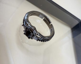 May include: A black ring with a large black stone and smaller clear stones set in a delicate, intricate design.