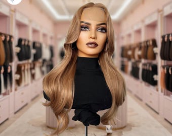 Puede incluir: Una peluca larga y ondulada de cabello humano castaño claro en una cabeza de maniquí. La peluca tiene un frente de encaje y está peinada con raya lateral.