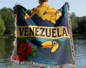 May include: A woven throw blanket with a colorful stained glass design featuring toucans, hibiscus flowers, and the word "VENEZUELA".