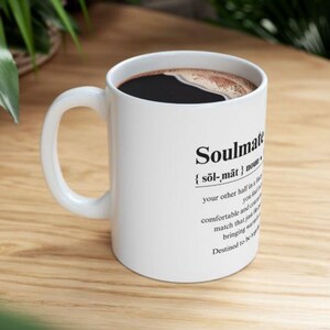 May include: White ceramic mug with a black handle. The mug has black text that reads "Soulmate {sol-mat} noun: your other half in a relationship, you feel comfortable and content, a match that just works, bringing magic. Destined to be together."