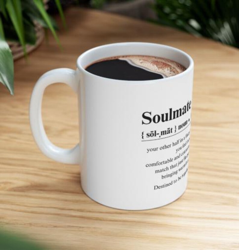 May include: White ceramic mug with a black handle. The mug has black text that reads "Soulmate {sol-mat} noun: your other half in a relationship, you feel comfortable and content, a match that just works, bringing magic. Destined to be together."