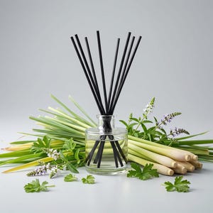 May include: A clear glass diffuser bottle with black reeds, surrounded by fresh lemongrass, green herbs, and small white and purple flowers. The diffuser is filled with a clear liquid, suggesting a natural fragrance.