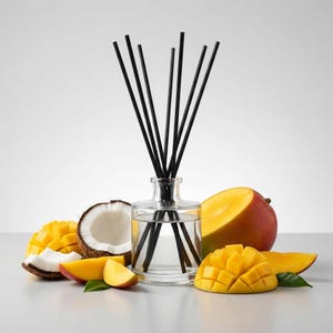 May include: A clear glass diffuser bottle with black reeds, surrounded by fresh mango slices, a whole mango, and a halved coconut. The mangoes are a vibrant yellow and red, suggesting a tropical theme.