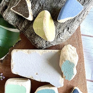May include: A collection of colorful, glazed ceramic tiles in various shapes and sizes. The tiles are arranged on a wooden surface and feature a variety of colors, including blue, green, yellow, and brown.