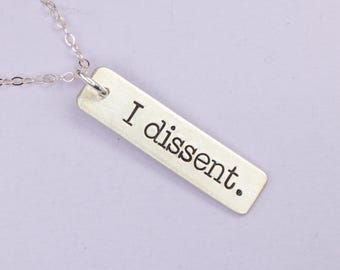 Peut inclure: Un collier en argent avec un pendentif rectangulaire qui dit "Je suis en désaccord."