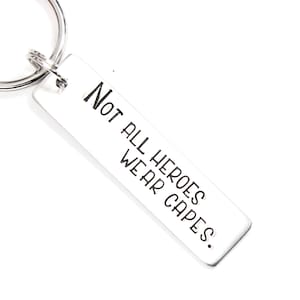 May include: Silver keychain with a rectangular tag that reads "Not all heroes wear capes."