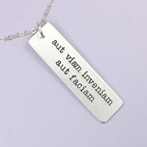 May include: Silver necklace with a rectangular pendant that reads "aut viam inveniam aut faciam".