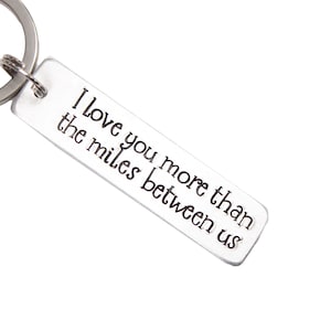 May include: Silver keychain with the text "I love you more than the miles between us".
